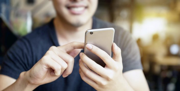 Happy man using smartphone at modern coffee shop, he chatting On