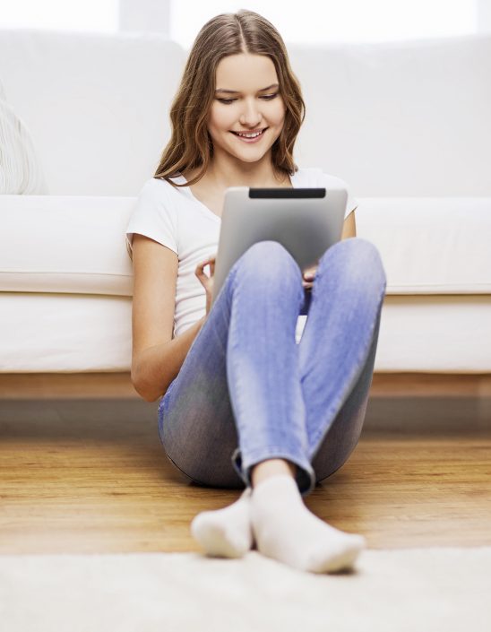 smiling teenage girl with tablet pc at home