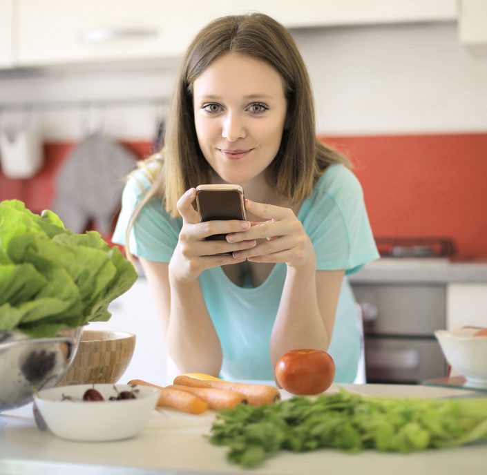 Girl using her phone white preparing some food